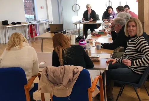 Participants writing at tables during an Emotional Fitness Repeating Patterns course