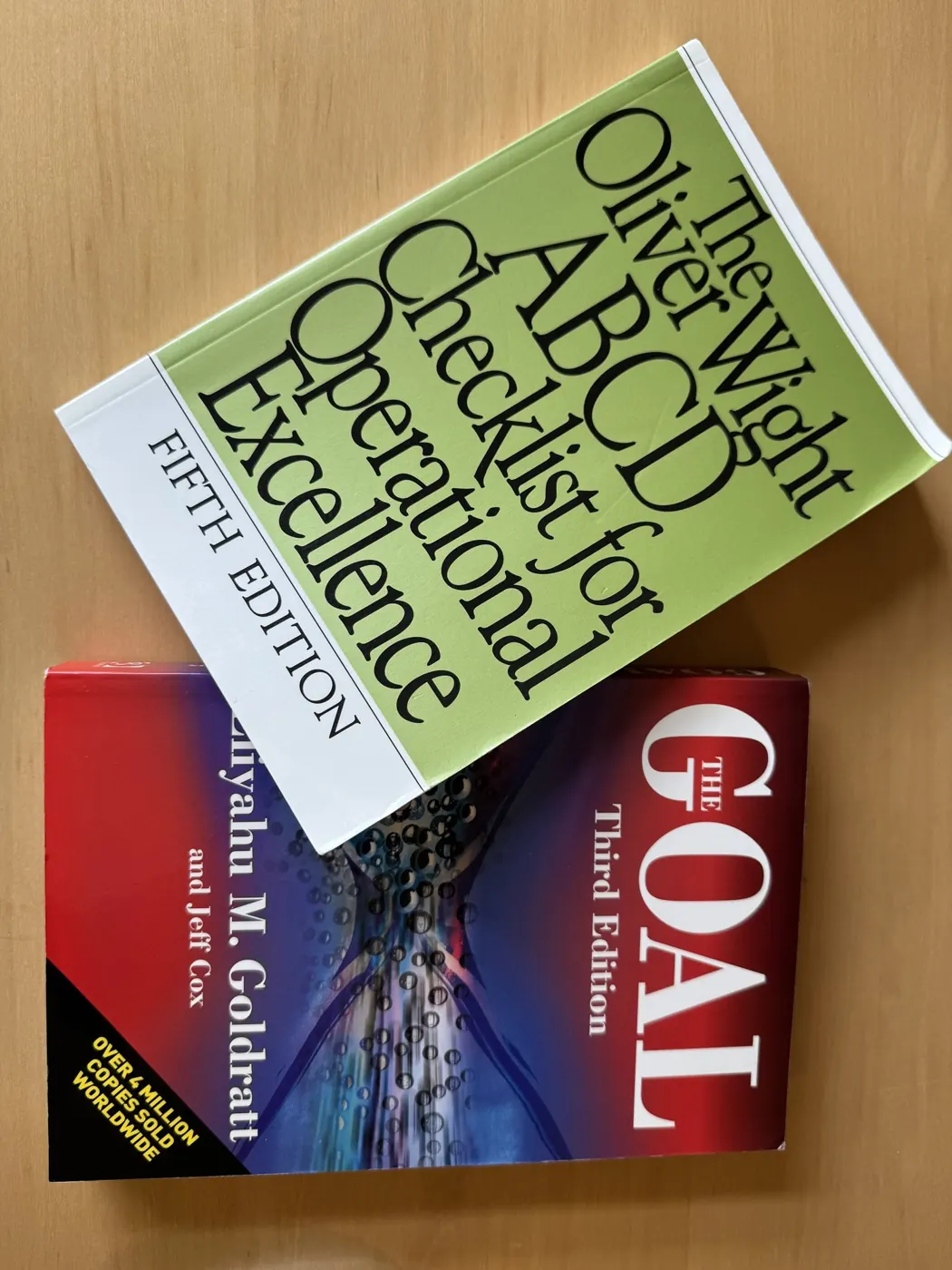Books The Oliver Wight ABCD Checklist for Operational Excellence and The Goal by Eliyahu Goldratt on a desk