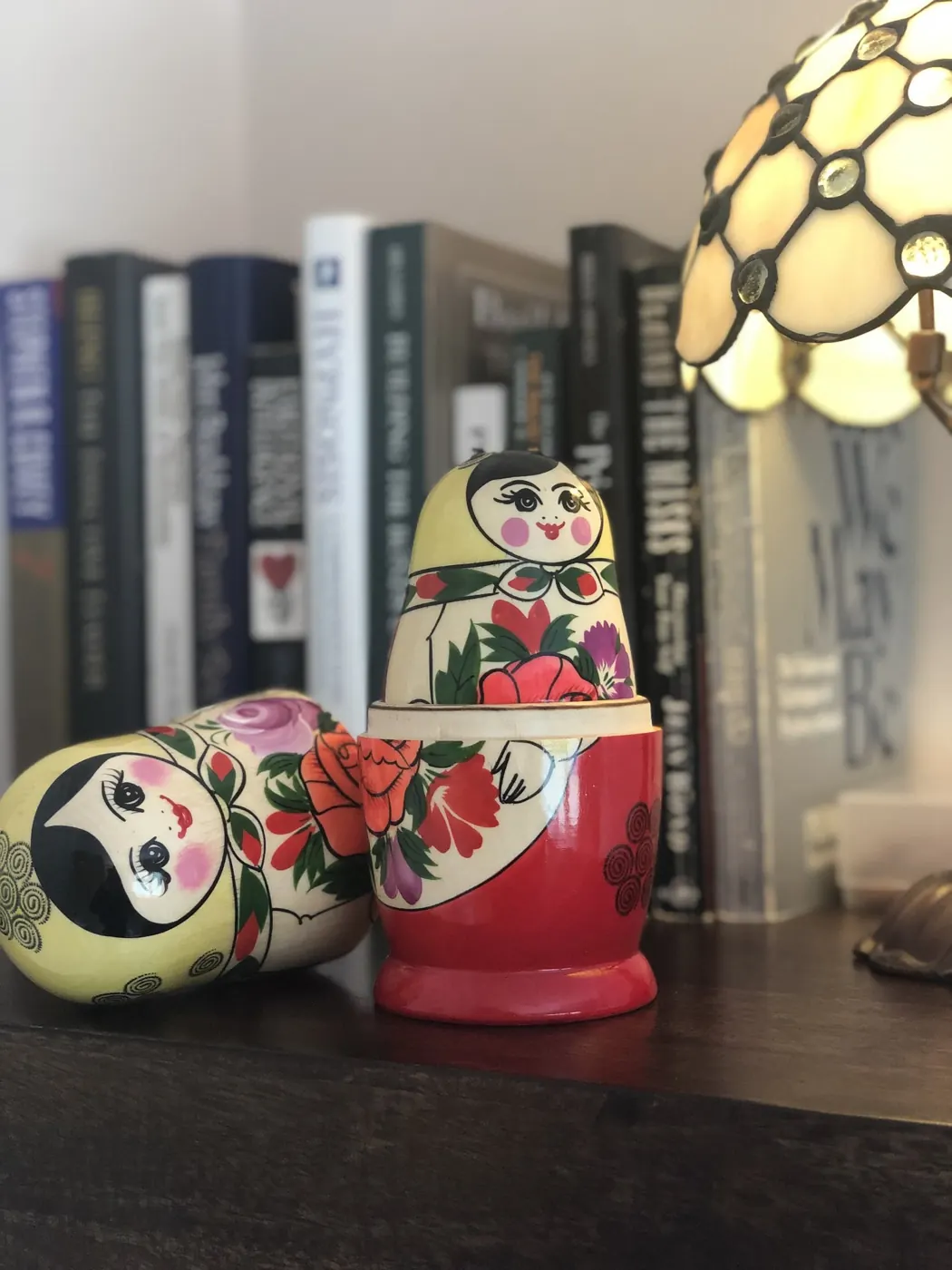 Two painted Russian dolls, one opened, in front of a row of psychology books